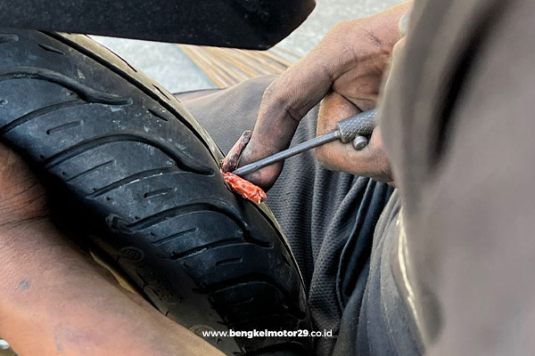 Mekanik Bengkel Motor 29 memperbaiki ban motor bocor sebagai layanan perbaikan ban dan velg motor.