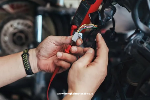 Mekanik melakukan perbaikan sistem kelistrikan motor menggunakan alat ukur digital.