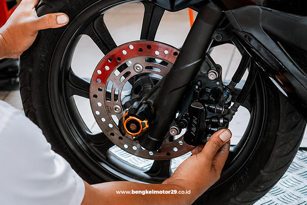 Mekanik melakukan perbaikan rem cakram motor untuk meningkatkan keamanan berkendara.